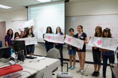 Students holding up paper "I heart LB" signs